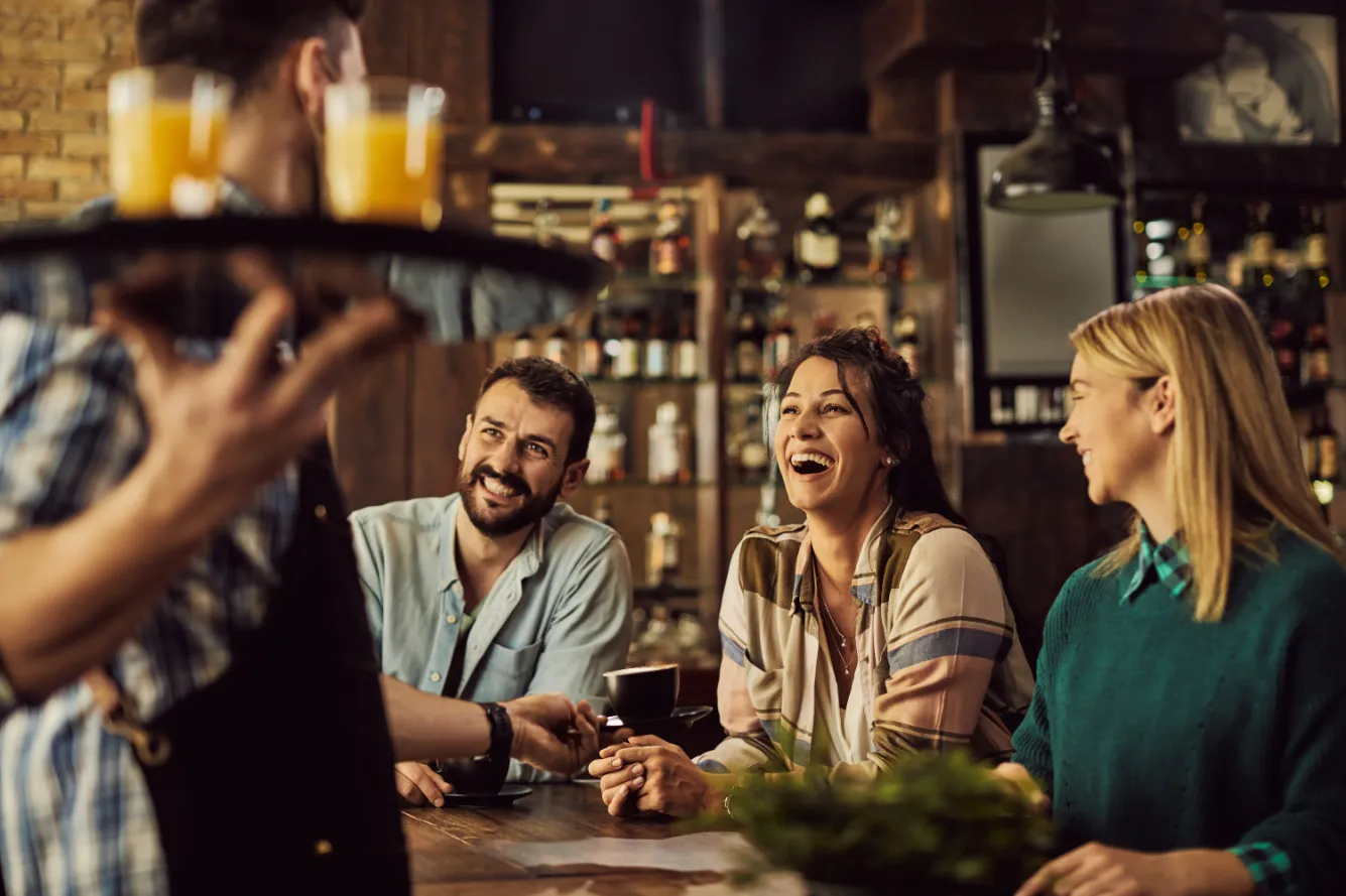 cheerful-friends-having-fun-while-talking-waiter-cafe